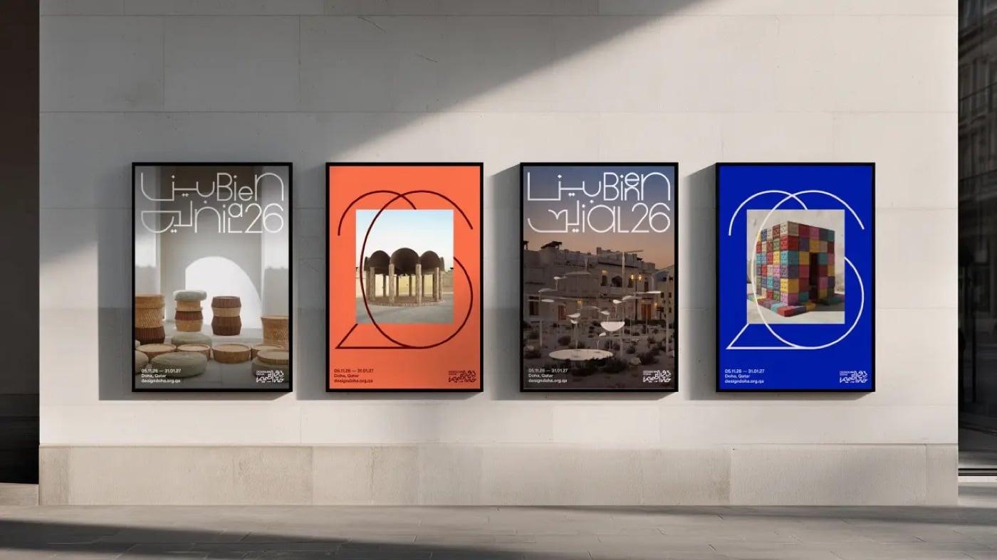 Bốn poster treo trên một bức tường đá sáng màu, xen kẽ poster ảnh tác phẩm có chữ nét mảnh chồng lên và poster màu cam, xanh dương