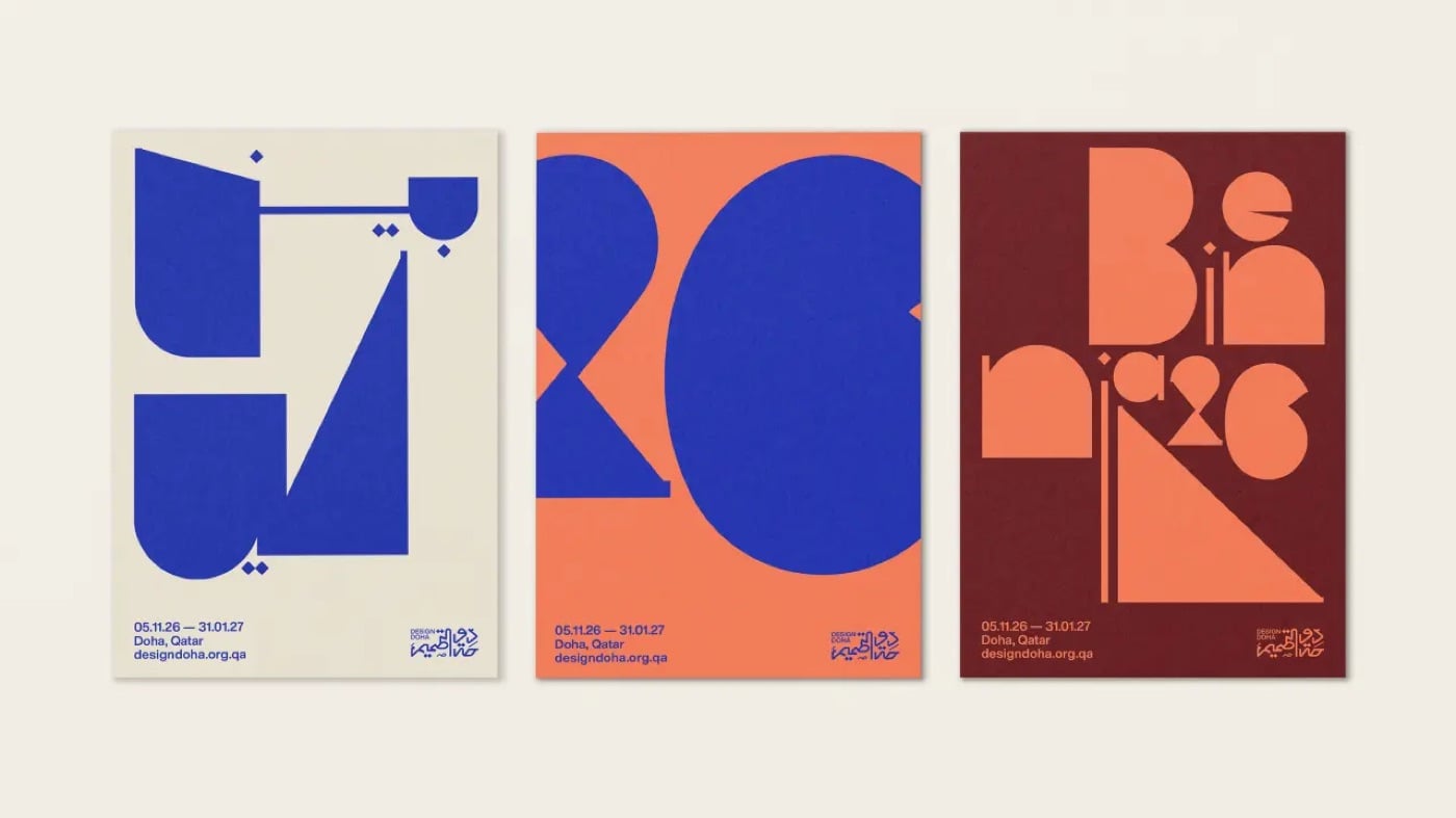 Ba poster đứng cạnh nhau: poster nền kem với chữ Ả Rập xanh dương dạng khối, poster nền cam với số 26 xanh dương rất lớn, poster nền đỏ nâu với chữ Biennale ghép từ khối hình học màu cam