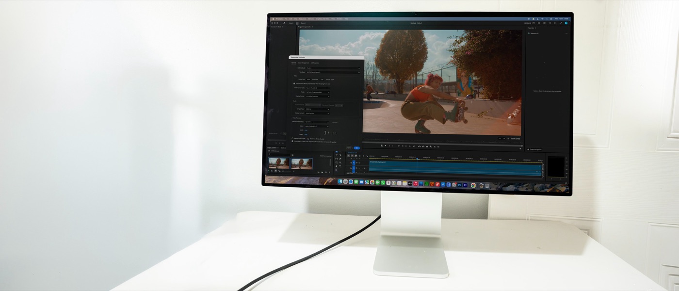 Màn hình Apple Studio Display XDR viền mỏng đặt trên bàn trắng, đang mở một phần mềm dựng video với khung hình người đi trên đường đất đỏ
