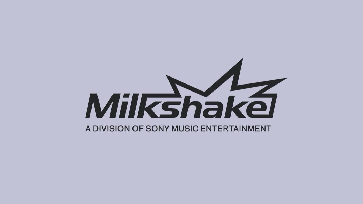 Logo chữ Milkshake màu đen nghiêng, phía trên có hình tia chớp nhọn, dòng chữ nhỏ A division of Sony Music Entertainment, trên nền tím lilac nhạt