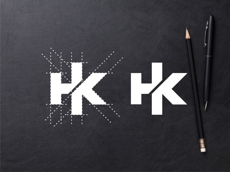 Monogram HK trắng trên nền da tối: nét đứng chung giữa H và K, kèm bản dựng với các đường chéo