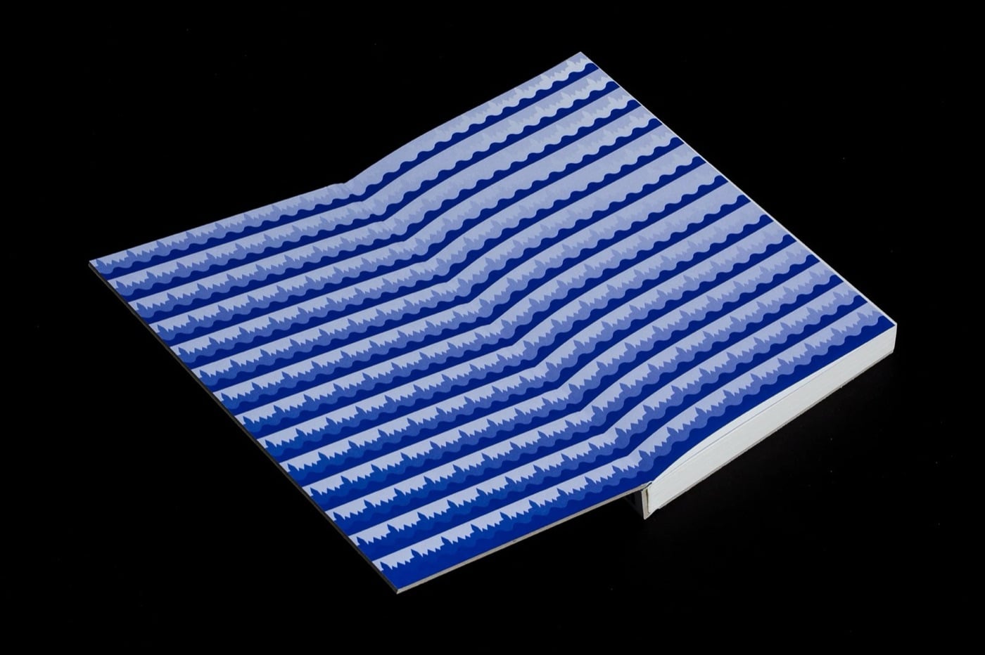 Trang trải trong vạt bìa in kín các sọc sóng ngang màu xanh cobalt và trắng, đặt trên nền đen