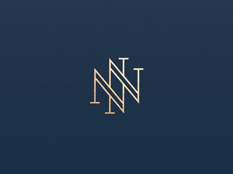 Monogram NN nét viền đôi màu vàng đồng trên nền xanh navy, hai chữ N có chân serif lồng lệch nhau