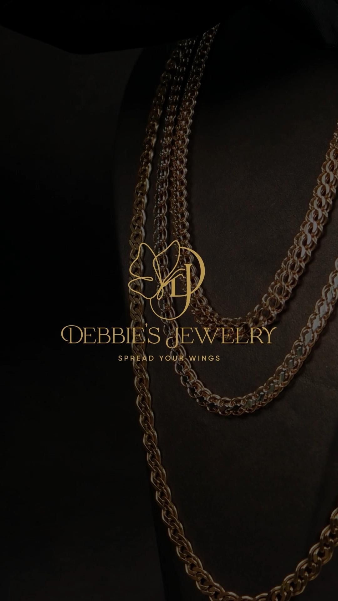 Logo Debbie's Jewelry màu vàng trên ảnh dây chuyền tối: chữ D và J lồng nhau với cánh bướm nét mảnh, chữ có chân bên dưới