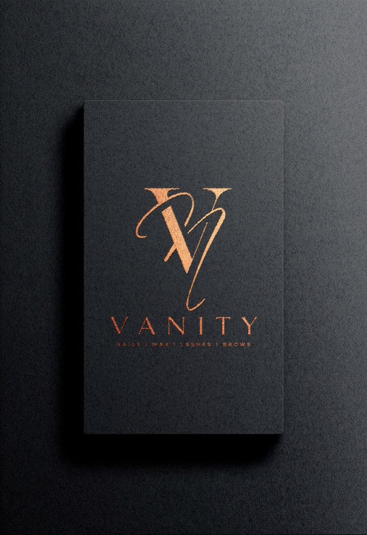 Logo tiệm nail Vanity ép nhũ đồng trên danh thiếp đen: chữ V có chân lồng với nét viết tay, chữ VANITY giãn rộng bên dưới