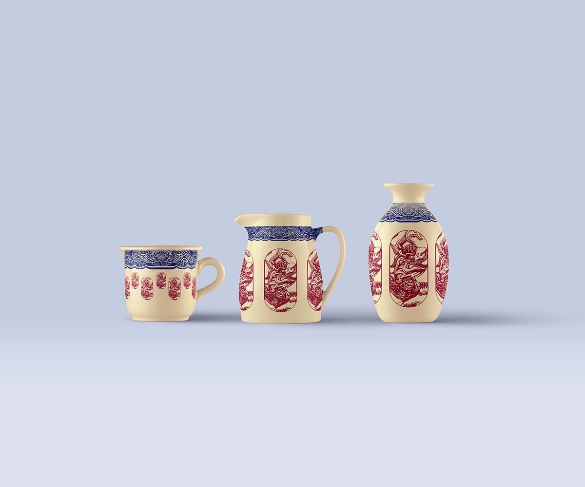 Mockup cốc, bình rót và lọ gốm màu kem có viền hoa văn xanh lam và hình con vật trong khung bầu dục màu đỏ