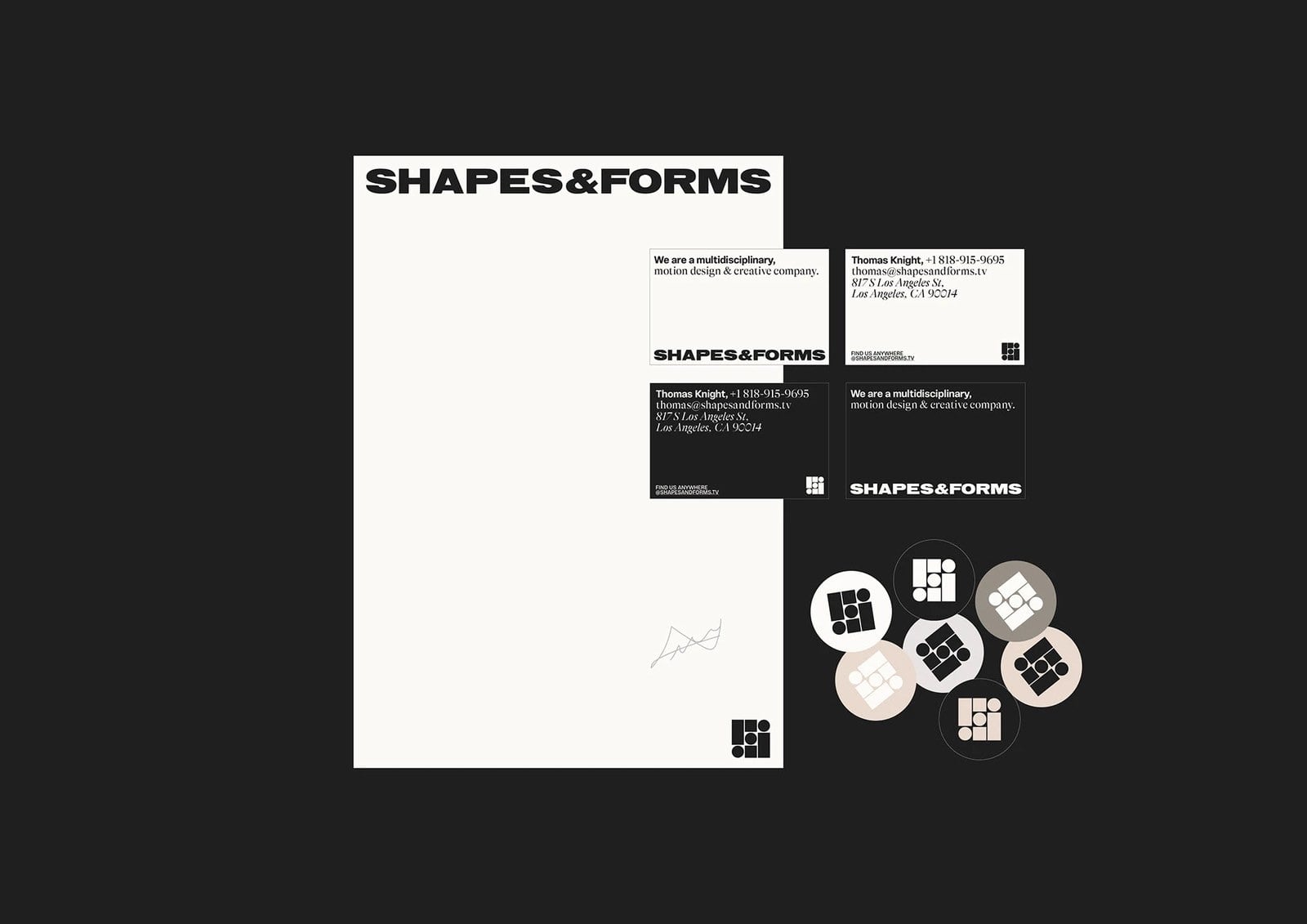 Bộ văn phòng phẩm Shapes and Forms trên nền đen: tờ giấy viết thư trắng ngà, danh thiếp màu than và kem, các nhãn dán tròn màu nâu xám, kem và đen
