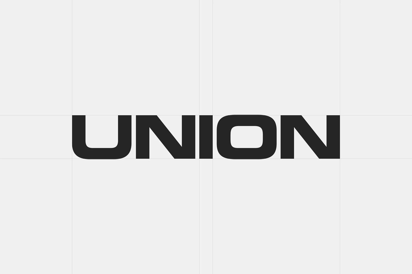 Chữ logo UNION màu đen kéo rộng, góc bo vuông, đặt giữa nền xám rất nhạt