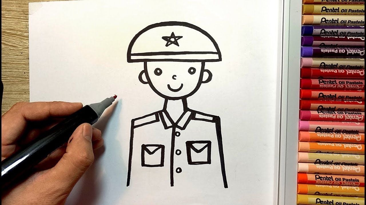 Bản vẽ nét đen chú bộ đội nửa người đội mũ cối có ngôi sao, áo hai túi ngực, tay người vẽ cầm bút dạ, hộp bút sáp màu bên phải