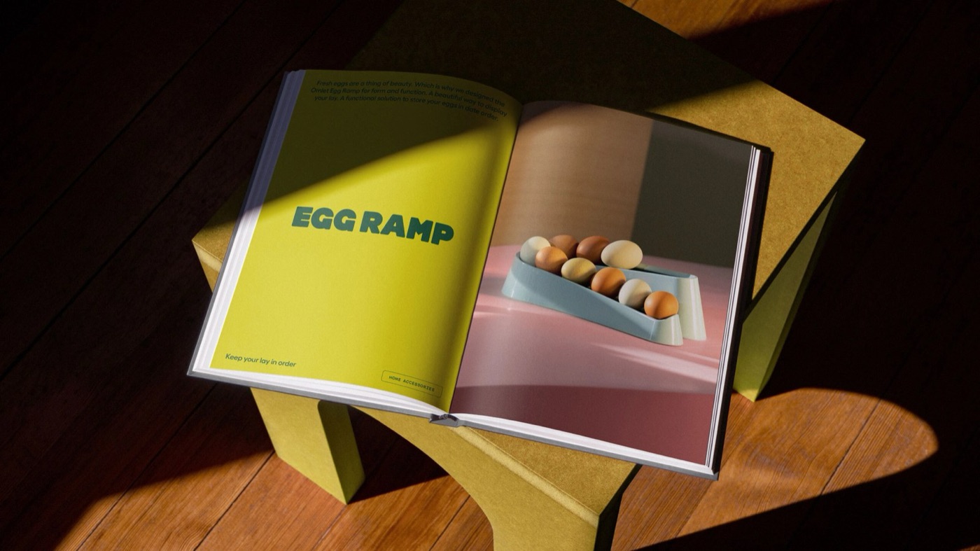 Cuốn sách bìa cứng mở trên ghế gỗ dưới nắng, trang trái màu vàng chanh có chữ EGG RAMP màu xanh, trang phải là ảnh những quả trứng nâu trên khay xanh nhạt